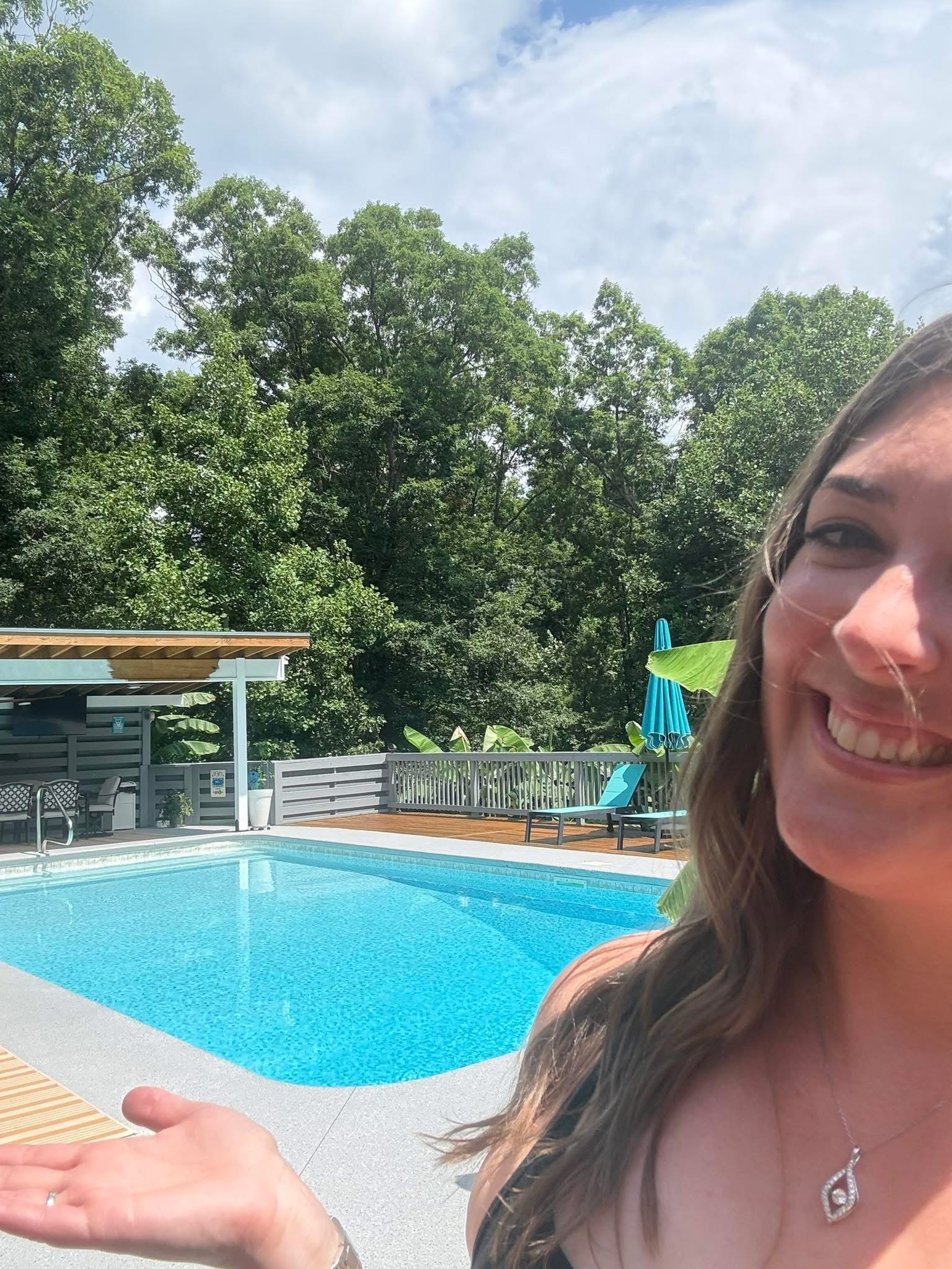 A smiling woman beside a backyard pool