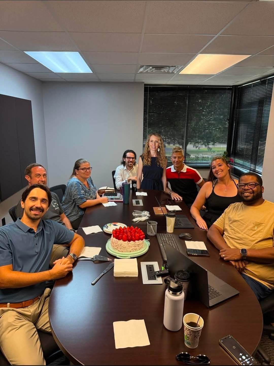 A group gathered around a table with a celebration cake